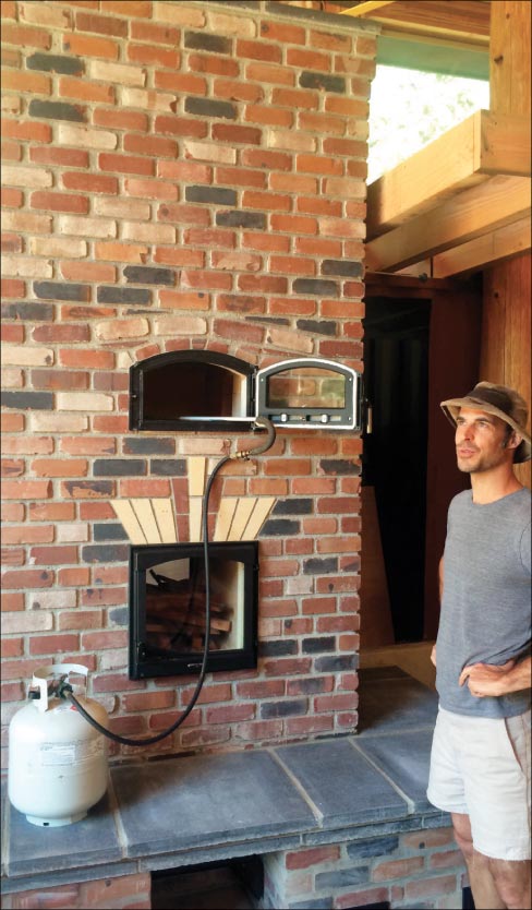 Mason Jason Temple stands next to a brick stove and baking oven with a firebrick core. Another common core utilized in masonry stoves for its excellent heat retention and release properties is soapstone.