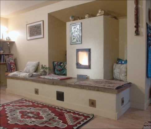 The multi-functional use of a masonry stove is well illustrated here with this example that acts as a warming bench for a human and their pet companions on chilly winter days.