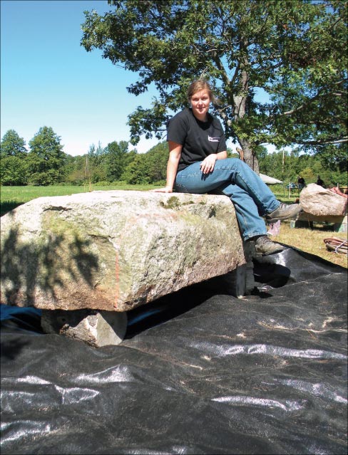 Artist Isabel Kelly seated on her massive Granite block, before starting to shape it.