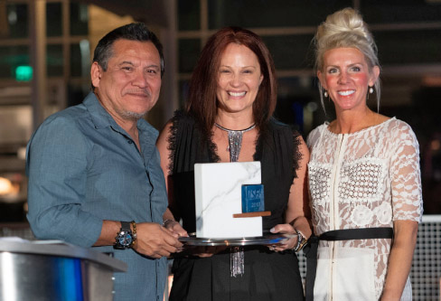 Hall of Fame inductee Erica Hussey receives the award with ISFA President Augie Chavez (left) and ISFA Executive Director Amy Miller (right).