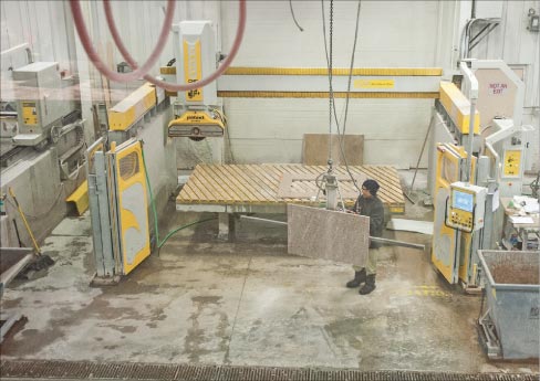 CNC saw operator Chansai Khanthachack uses one of the shop’s 5 Manzelli lifters to transfer a top.