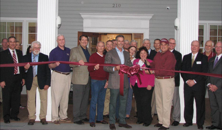 Dignitaries at the Alexander Guest House ribbon-cutting ceremony are: front, from left:  David Bradshaw, Joseph Lee, Ray Evans, Mark Watson (City Manager), David Wilson,  Rick Dover (middle), Teresa Scott, Mayor Warren Gooch (with scissors),  Rick Meredith, Parker Hardy (President of the Oak Ridge Chamber).