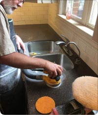 Refinishing dark Corian – starting with diamond-impregnated pads on an orbital sander, and replacing original medium gloss 