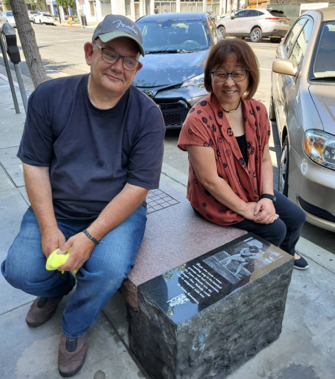 David Bonasera and Pam Yoshida on a restored granite bench  showing the area history of Sumo Wrestling. Yoshida is a  production coordinator for a local architectural firm, a member of the Construction Specifications Institute, and is heading up  the community response on the Japantown revitalization project.