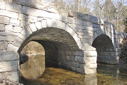 Wilmore Culvert project. The wood forms are called “centering” or “falsework.” The culvert was at a slight angle to the road, so the centering extends a bit beyond the face. Both vaults are laid-up at the same time, then the centering is removed, leaving a self-supporting arch.