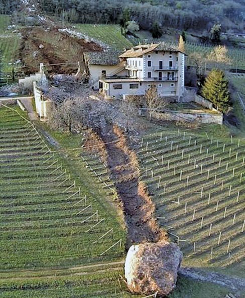 In this photo provided by Tareom.com, on January 23, 2014, a huge boulder has come to rest after it missed a farm house by less than a meter, destroying the barn, and stopping down hill in the vineyard, while a second giant boulder, which detached during the same landslide on Jan. 21, 2014, stopped next to the house, in Ronchi di Termeno, in Northern Italy. According to reports, the Trebo family living there was unharmed in the landslide. The lost grapevines are irreplaceable, but can always be replanted. Photo: Markus Hell, AP