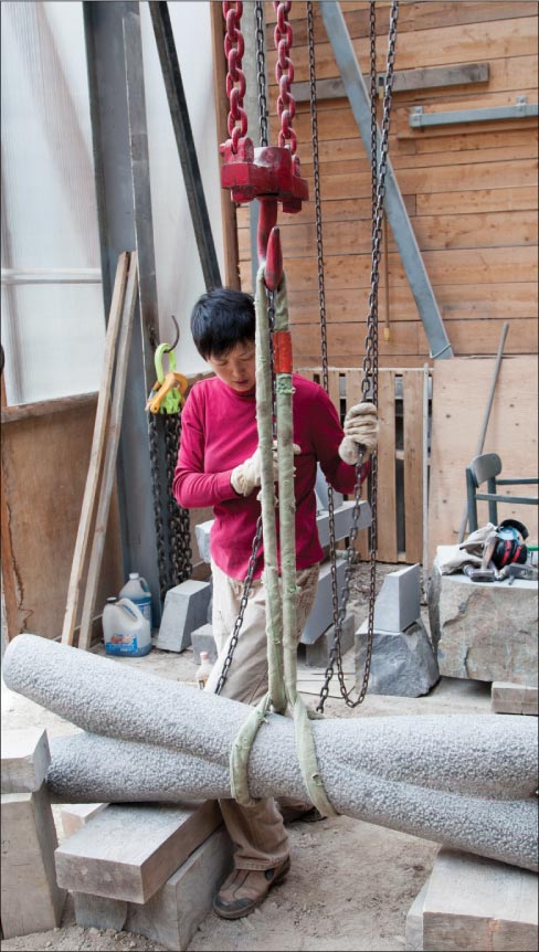 Jett Mist, the black granite used to make “Form of X” was quarried in Virginia and according to Hoshi, soft. Here she gently rolls it over to make the final pass of bush hammering.