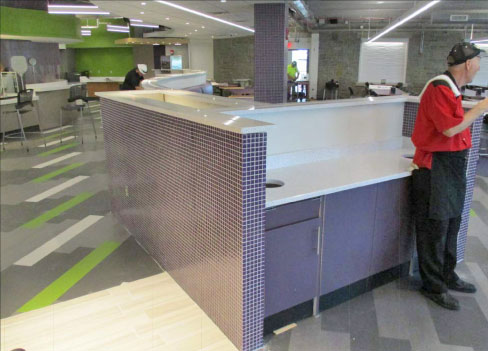 A recent Niagara University project (shown in progress) included a refit of solid surfaces throughout Clet Hall. Above and below: cafeteria installation of a long, curved bench barrier separating seating and the serving line, and the tray return area.