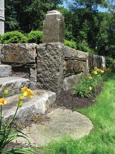 Blocks reclaimed from the Essex-Merrimac Drawbridge bridge granite piers have found a new purpose as retaining wall material.  Reclaimed granite curbing and a half mill stone unearthed on this property add to the antique look.