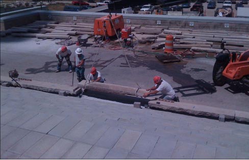 Resetting treads on the Kansas Statehouse front entrance stairs. A stack of replacement treads can be seen in the background 