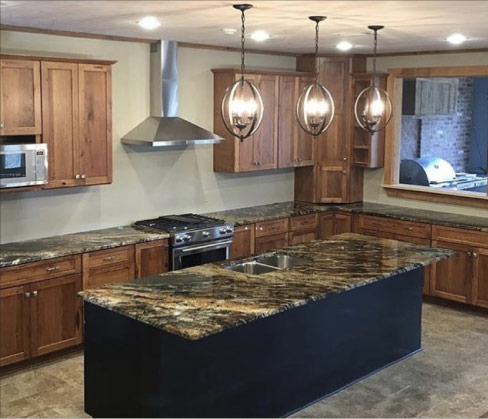 Magma Granite island and perimeter countertops add movement and visual interest to this modern kitchen. The adjacent room, seen through the pass-through features an outdoor kitchen with a built-in grill.