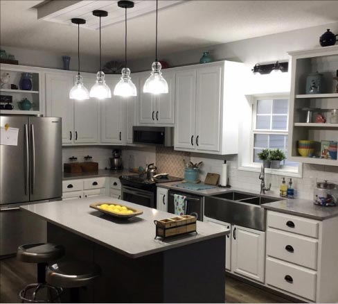 This Farmhouse kitchen by Premier Countertops mixes traditional with the modern in this cozy setting.  Durable LG Viatera Lento countertops and a modest size island keep the kitchen space from being cramped, and provide an ample workspace and dining area. The pattern tile backsplash and contemporary subway tiles work to create a clean look with a warm spot of color interest. Says Wadell, “We have a lot of customers who ask about tile for their backsplashes and floors, so we decided to move into that portion of the business.”