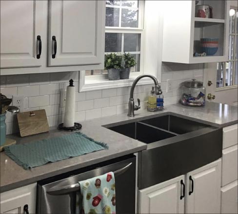 This Farmhouse kitchen by Premier Countertops mixes traditional with the modern in this cozy setting.  Durable LG Viatera Lento countertops and a modest size island keep the kitchen space from being cramped, and provide an ample workspace and dining area. The pattern tile backsplash and contemporary subway tiles work to create a clean look with a warm spot of color interest. Says Wadell, “We have a lot of customers who ask about tile for their backsplashes and floors, so we decided to move into that portion of the business.”