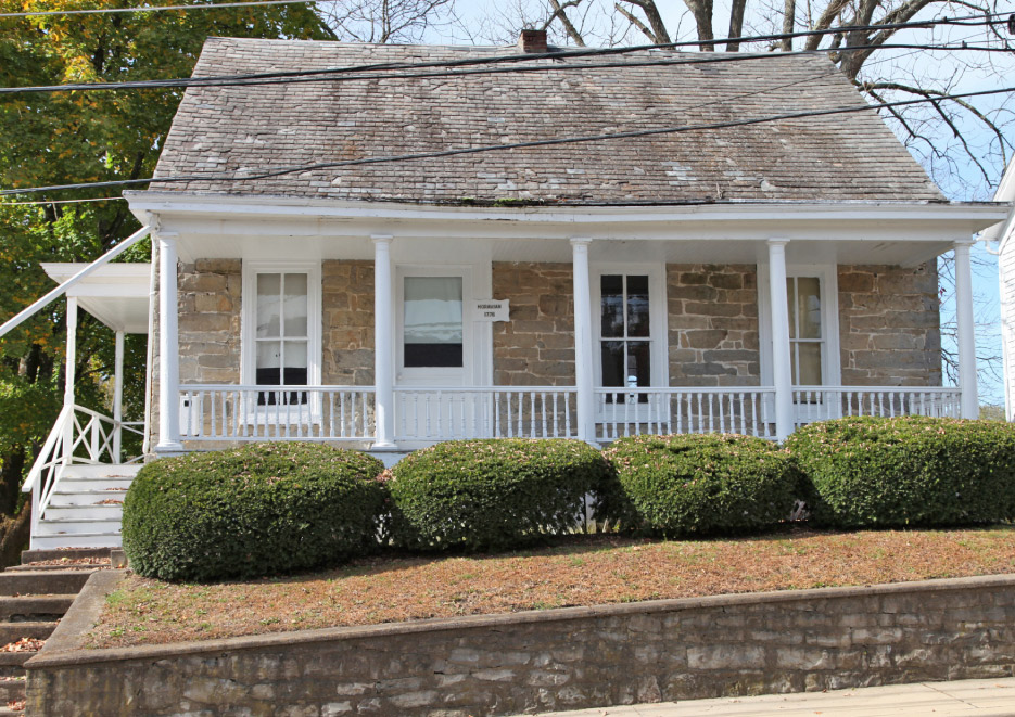 This trim cottage with a natural slate roof was built in 1776. The front and side porches are modern additions.