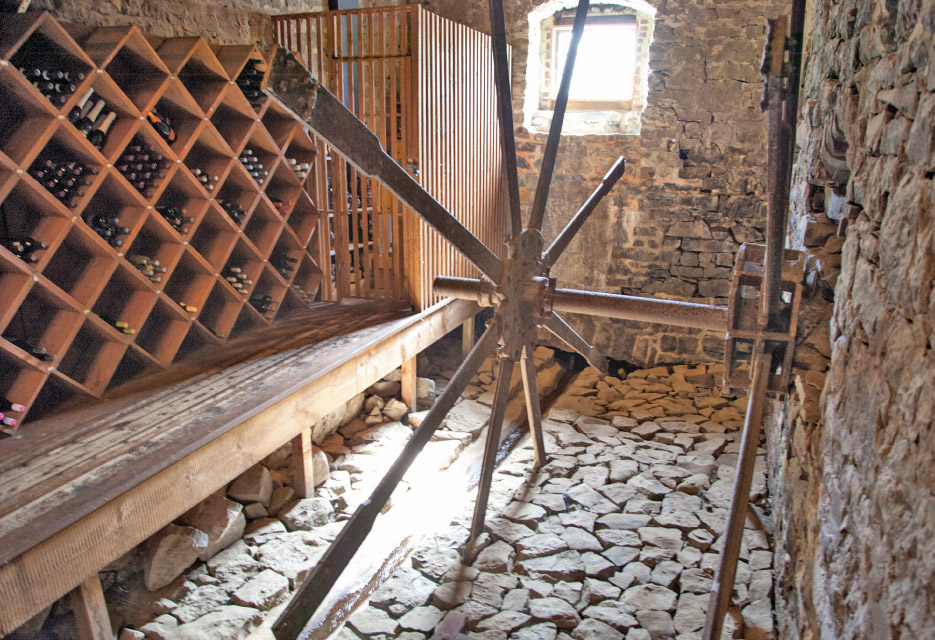 The remnants of this water wheel serve to inspire curiosity while the wine on the left is kept at a perfect temperature in the cool, stone-lined room.