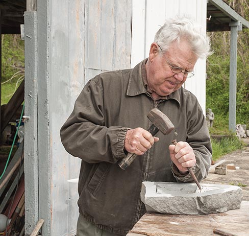 Bill Ralston, at his Bell Buckle, TN studio, roughs out a limestone sample of his arts awards sculpture with hammer and chisel.