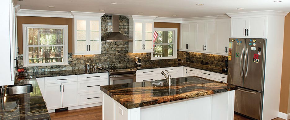 This updated version of a traditional white kitchen with frosted glass-front cabinets features a dramatic Hurricane granite island chosen for movement in the stone and a three-sides wrapped backsplash with large-format brick tiles.