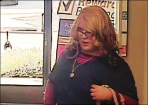 This Friday, April 3, 2015, image from surveillance video provided by the Santa Cruz Police Department shows a wanted man dubbed the "Mrs. Doubtfire" bandit because he was disguised as a woman during a bank robbery in Santa Cruz, Calif. He wore a wavy blonde wig, thick-framed glasses and navy blue hospital scrubs, and carried a purse. About an hour later the same man in the same outfit handed a teller a note that demanded money at a second US Bank branch in Santa Cruz. The suspect got away with an unknown amount of money.