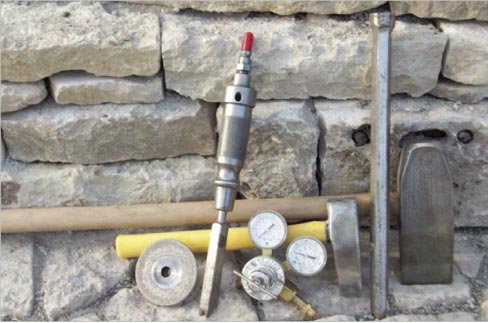 Some of Stander’s tools of the trade against a repaired wall using recovered stone.