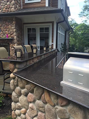 This rustic outdoor kitchen features granite tops set on fieldstone.