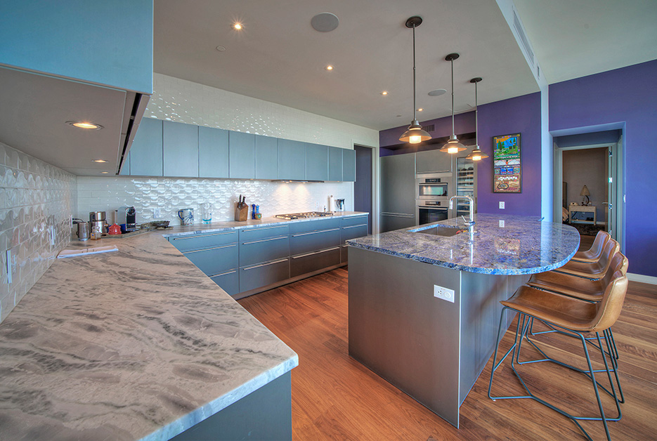 Blue Bahia granite Island is the colorful centerpiece of this La Vaca Hotel Suites kitchen, with Silver Storm marble perimeter countertops as an elegant, neutral color contrast.