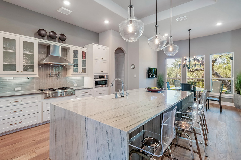 Bishop Pond development kitchen features White Macaubas quartzite island with waterfall edge and a farmhouse sink.