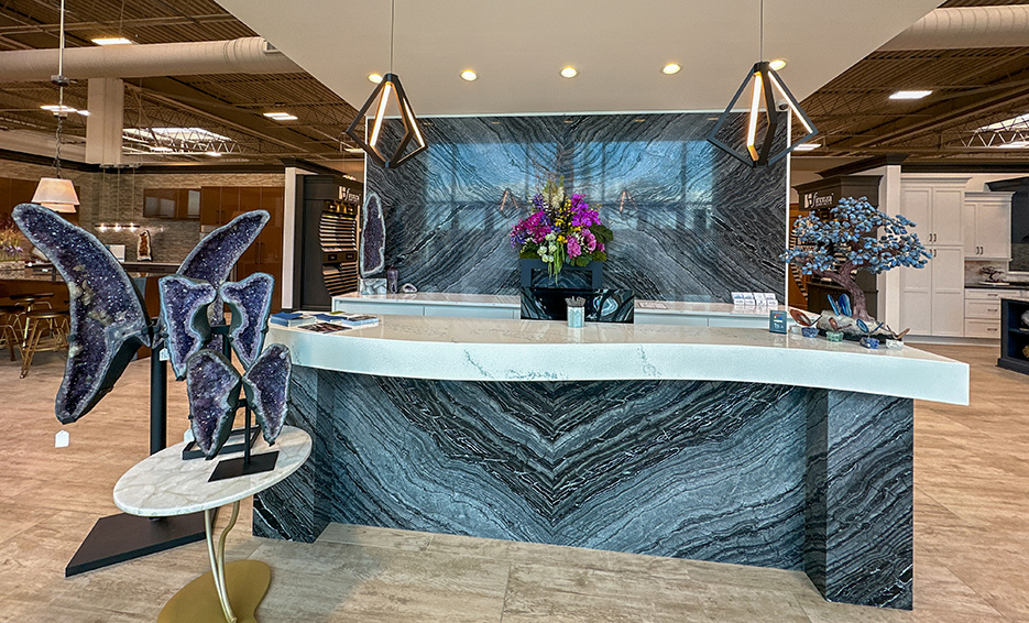 The Firenza Stone showroom features several vignette kitchens. This book matched Silver Wave marble reception desk front and wall greets visitors to the showroom. 