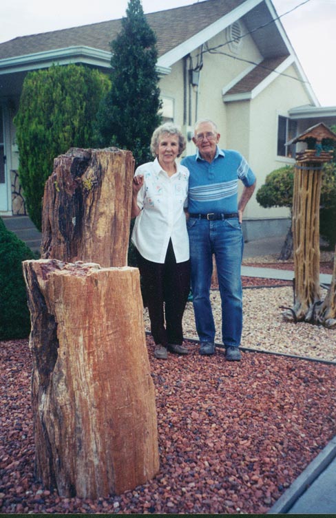 Bryant and Edna Washburn stand in their petrified wood garden in front of their home