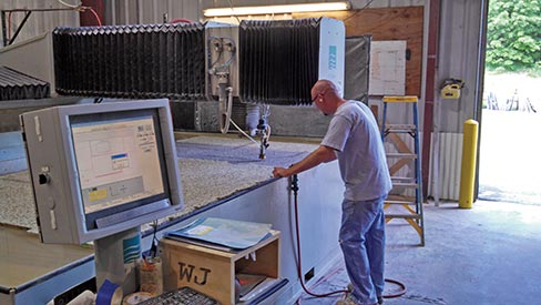 Andrew Koontz of B.C. Stone checks the progress of their water jet, programmed to slice up a full slab job. Co-owners Rod Bair and Travis Collins each have over 25 years of experience in the countertop business.