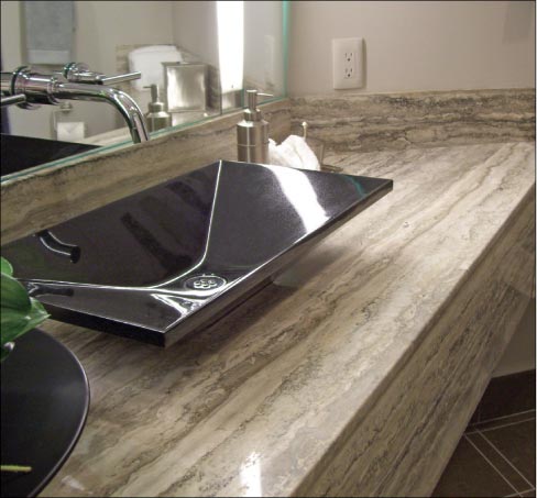 This custom bath features a Silver travertine vanity, backsplash and drop apron paired with an Absolute Black granite vessel sink.