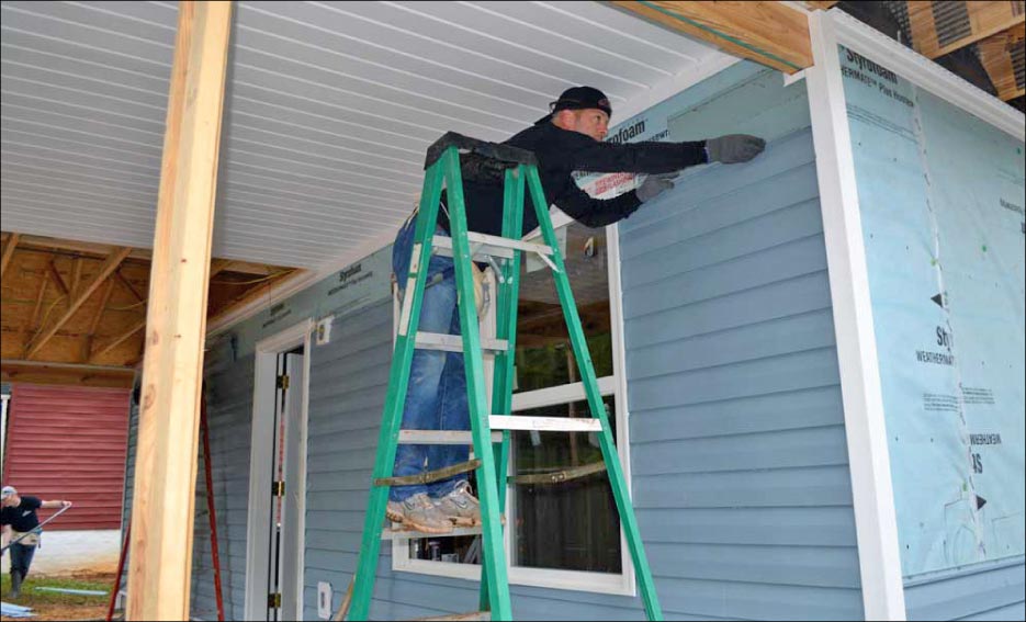 Stimac installs siding on the home.