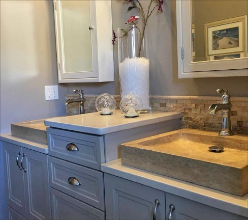 Double vanity with matching vessel sinks is a decorative contrast to the vanity tops and the chiseled edge backsplash. 