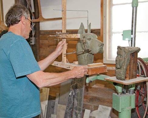 Brent Wilson, owner of Proctor Marble Company in Proctor, Vermont works with a clay model preparing to bring out the dog’s head that resides within the granite.