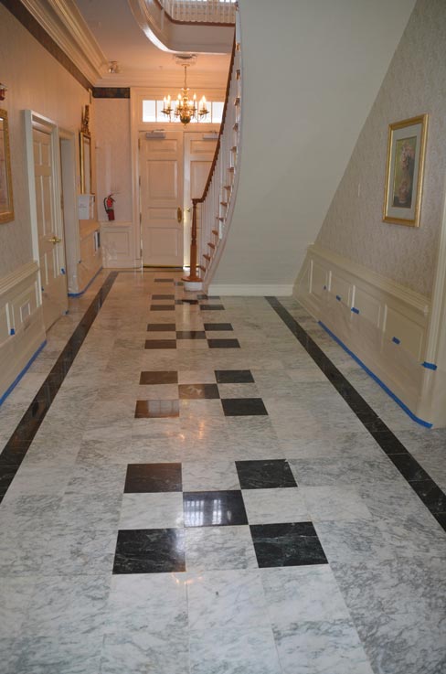 The inlaid marble entry hall with the wainscot masked and the floor prepped for restoration: removing over four decades of dirt, and repairing deep scratches in the marble.