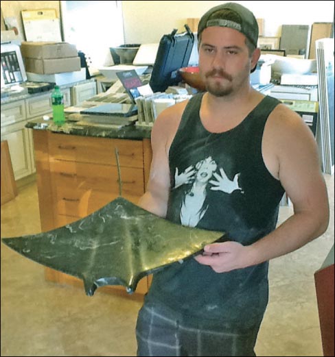 Austin Clay with a marble manta ray, one of his many shop remnant sculptures.