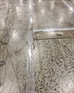 This example of a failed  floor coating and joint fill at an industrial plant shows the gaps, fissures and cracking typical with coatings failures from heavy floor traffic.