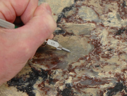 Figure 7: Areas with pools of resin are often the softest part of a manufactured quartz surface. On this sample of Cambria Shirebrook, the resin is lightly scratched by a tool with a Mohs hardness of 6. Image courtesy of Karin Kirk.