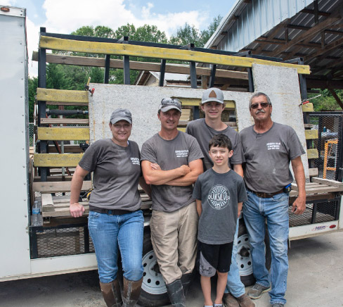 Loaded and ready to roll. Stafford built a custom trailer with an enclosed cab to hold jobsite tools and machines like his No-Lift Cart, with ample side A-frame storage to transport jobs. From left: Nina Franklin, Josh, Max and Alex Stafford, and founder Chuck Stafford.