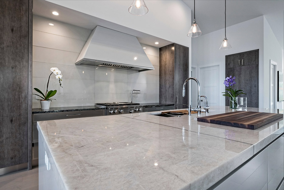 This high-end kitchen island is cristallo quartzite tied in with a backsplash of glass tile panels.