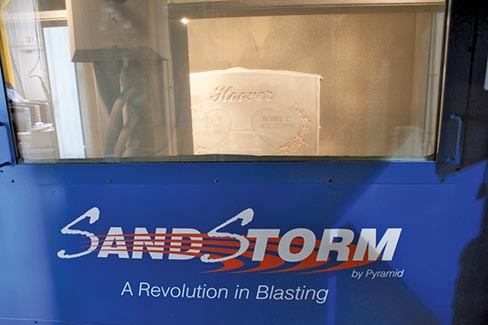 A monument in process in the blasting booth, behind the Sandstorm Blast Curtain