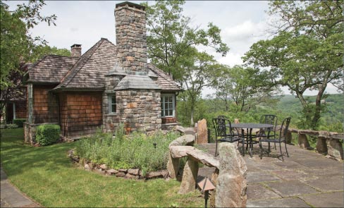 A view from the gate side of the Tuxedo Park home shows Mike’s Jamieson’s rustic style. Mike did every bit of stonework you see including granite steps, which he rolled in on broom handles to set. “The owner wanted a Bruce Price look that blends into the hillside.” Bruce Price was an American architect and the innovator of the Shingle Style. His unique designs, used during the construction of cottages in Tuxedo Park, New York greatly influenced some of the finest architects of the twentieth century, including Frank Lloyd Wright and Robert Venturi. Emily Post was Bruce Price’s daughter and was the famed author who wrote the book Etiquette.