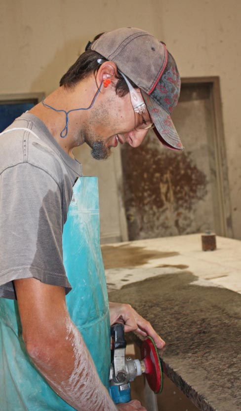 Michael Collins wet polishes a semi-final grit on a soon-to-be half-slab island at one of the 4 polishing stations in the shop.       