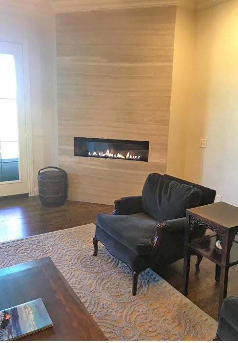 A Silver Cream travertine full wall fireplace surround creates a beautiful focal point in this comfortable family room.