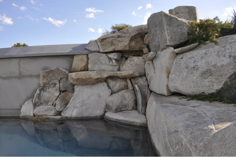 Local stone was used to create this naturalized outcropping for a waterfall and swimming pool retaining wall in Cape Elizabeth, Maine.