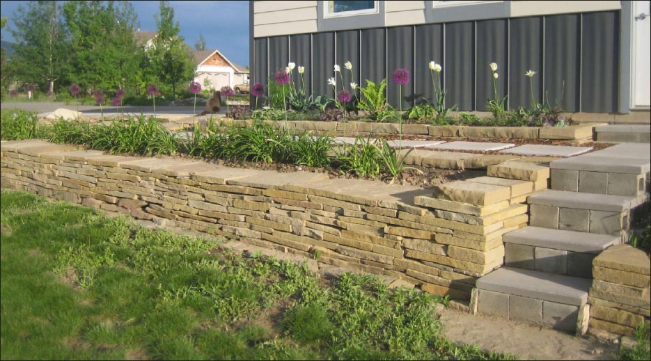 Dry stone stack retaining wall and planter with capstone flags, built by Kirk. 