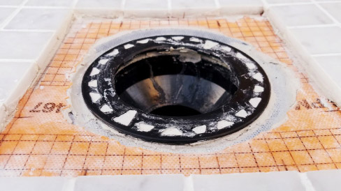 Integrated bonding flange drains create a little dam around the drain opening; not what you want in your marble tile shower installation.