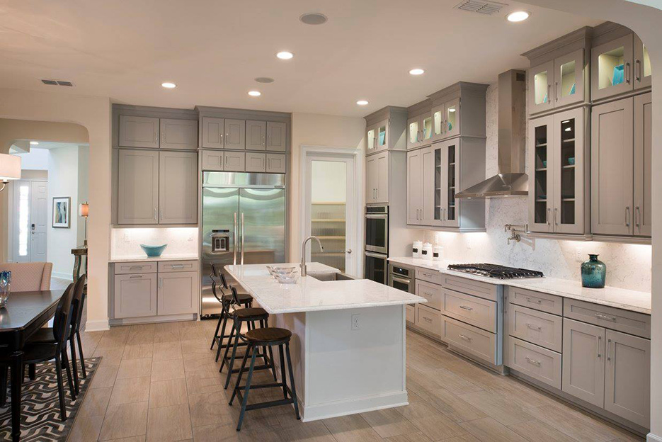 This spacious kitchen features a counter-to-ceiling splash behind the range hood, and custom glass-fronted cabinets.