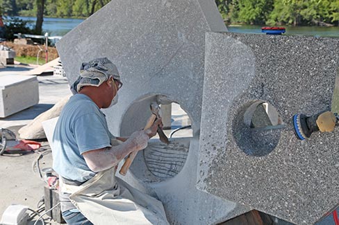 Inch by inch, sculptor Shan-Chi Teng of Taiwan chips ever deeper towards the completion of his multi-angle contribution to the symposium