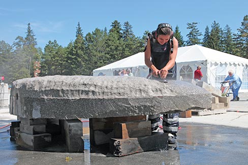 With only one week to go, Project Director Tilan Langley dons boots, apron, and ear protection to assist sculptor Ton Kalle in the final phase of polishing