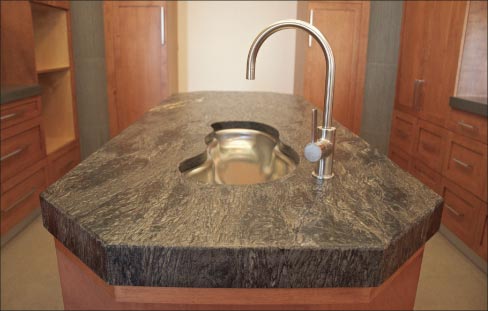 Leather-finished, mitered and laminated octagonal island of Black Forest granite features an elegant, precise custom sink cut-out.